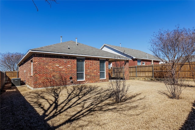 rear view of property with brick siding, cooling unit, and a fenced backyard