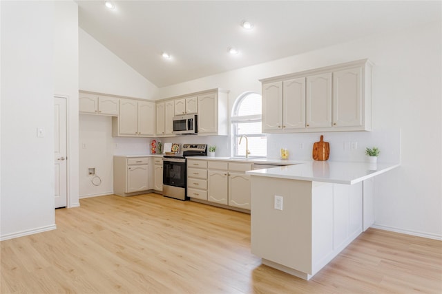 kitchen featuring light countertops, appliances with stainless steel finishes, light wood-style floors, a peninsula, and baseboards