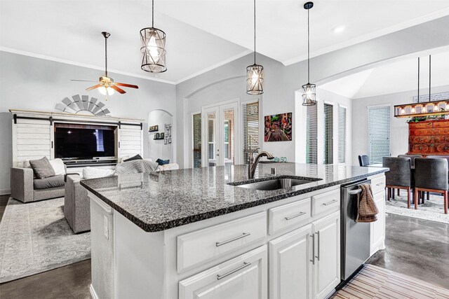 kitchen featuring french doors, open floor plan, a kitchen island with sink, a sink, and dishwasher