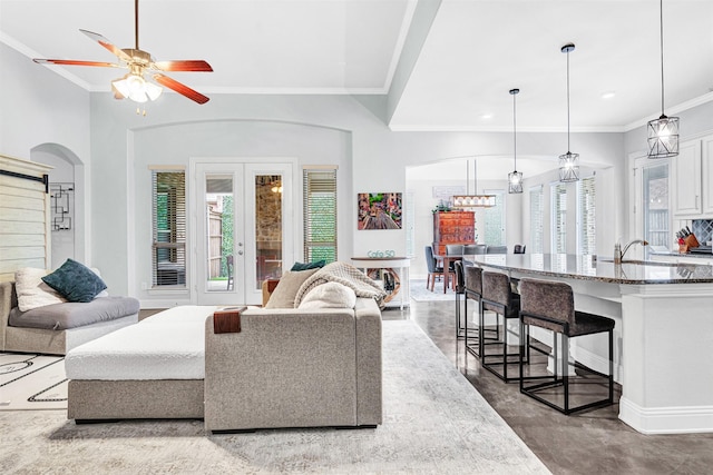 living room featuring arched walkways, french doors, a wealth of natural light, and crown molding