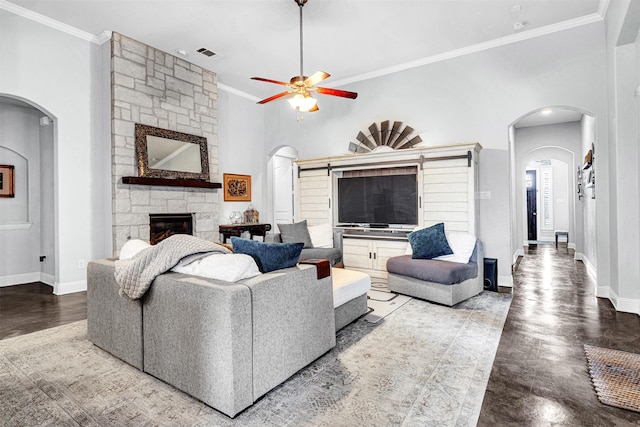 living area with arched walkways, visible vents, a stone fireplace, and baseboards