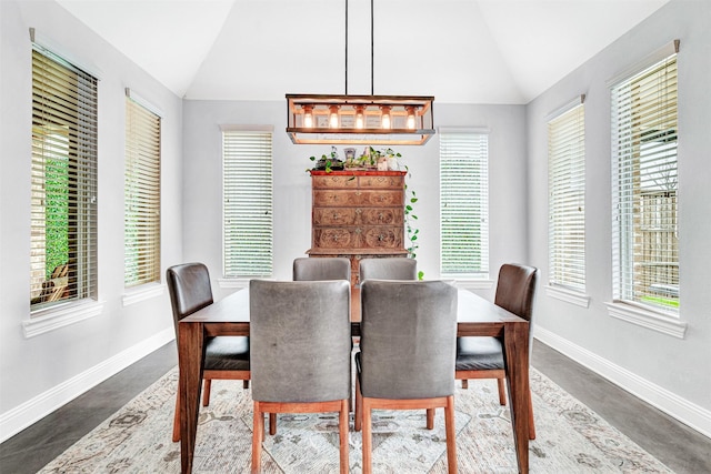 dining area with vaulted ceiling, concrete floors, and baseboards