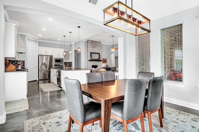 dining space with baseboards, a ceiling fan, ornamental molding, a fireplace, and recessed lighting