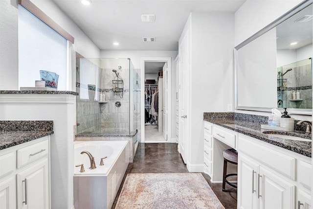 bathroom with a stall shower, visible vents, a garden tub, a walk in closet, and vanity