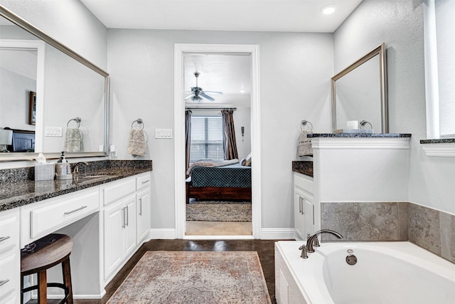 bathroom with a garden tub, ensuite bathroom, ceiling fan, vanity, and baseboards