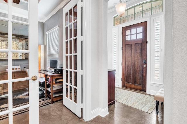 entrance foyer featuring ornamental molding, french doors, concrete flooring, and a textured wall