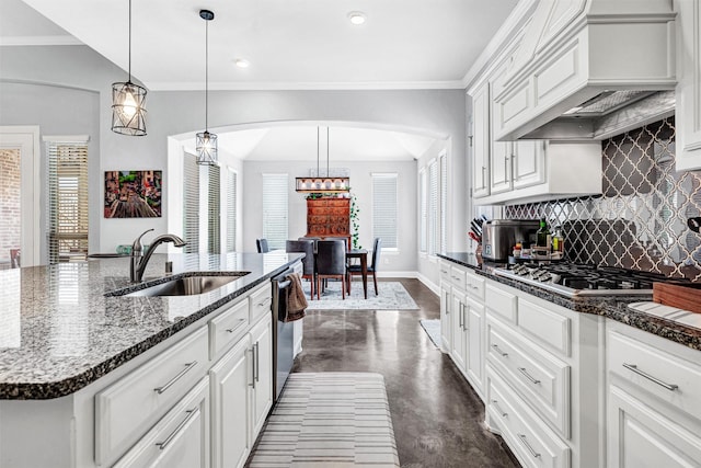 kitchen featuring arched walkways, premium range hood, a sink, and white cabinetry