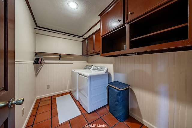 laundry area with a textured ceiling, light tile patterned flooring, a wainscoted wall, independent washer and dryer, and cabinet space