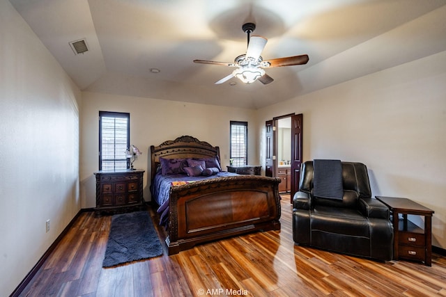 bedroom with a ceiling fan, wood finished floors, visible vents, and baseboards