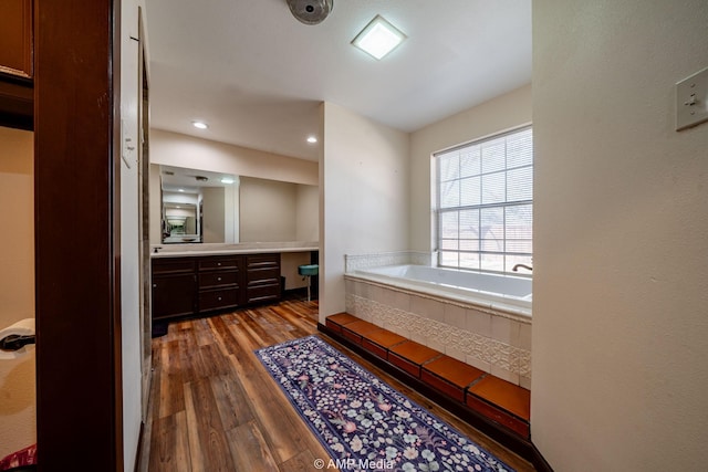 bathroom with a garden tub, wood finished floors, and vanity