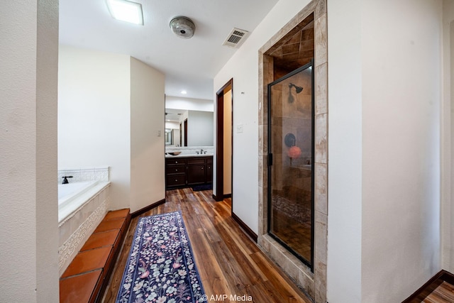 full bath featuring a garden tub, wood finished floors, vanity, visible vents, and a stall shower