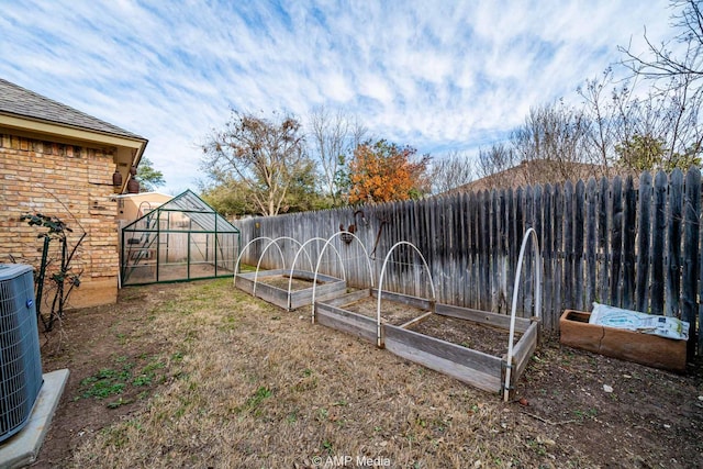 view of yard featuring central AC unit, a fenced backyard, an outdoor structure, a garden, and an exterior structure