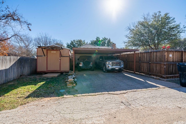 view of car parking with a carport, driveway, a shed, and a fenced backyard