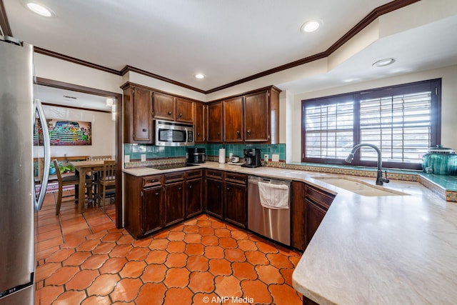 kitchen featuring appliances with stainless steel finishes, light countertops, a sink, and decorative backsplash