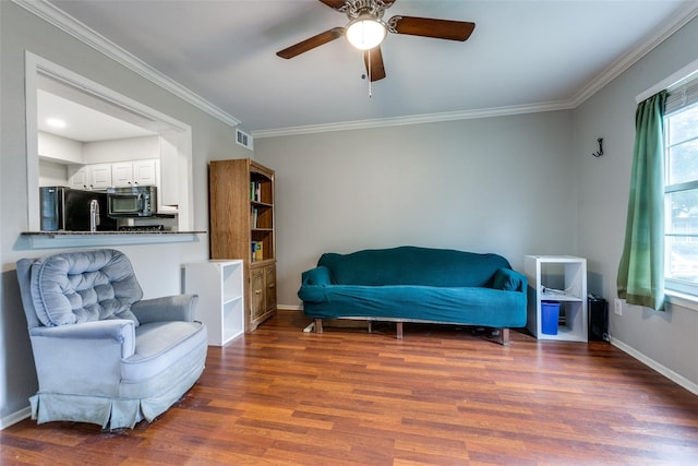 living area with baseboards, visible vents, ceiling fan, wood finished floors, and crown molding