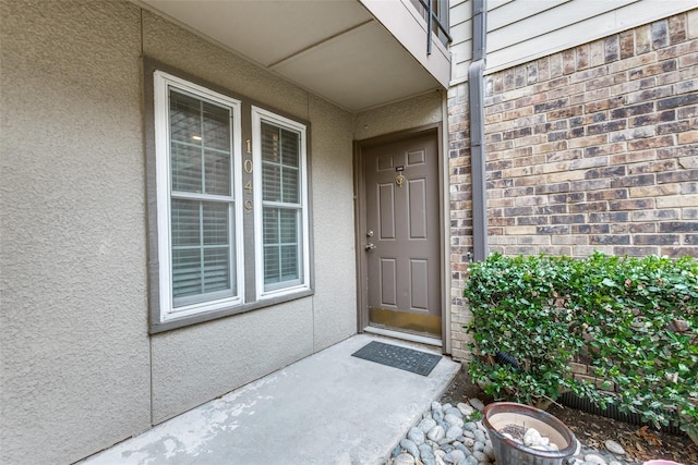 property entrance featuring stucco siding and brick siding