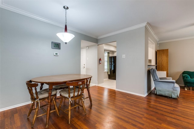 dining space with baseboards, wood finished floors, and ornamental molding