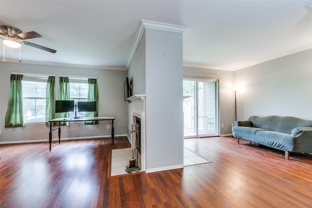 living room featuring a fireplace with flush hearth, crown molding, wood finished floors, and baseboards