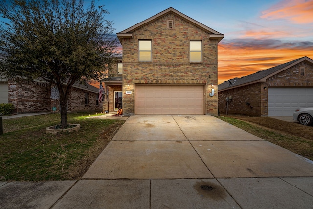 traditional home with an attached garage, driveway, brick siding, and a front yard