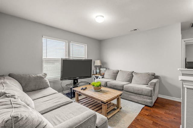 living area with visible vents, baseboards, and wood finished floors