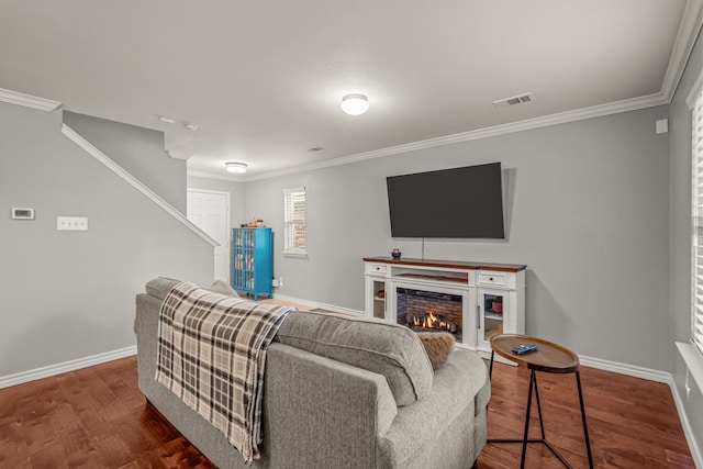 living area with a warm lit fireplace, dark wood finished floors, visible vents, and baseboards