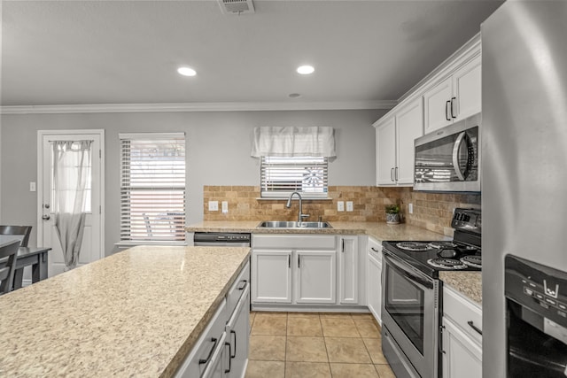 kitchen featuring appliances with stainless steel finishes, ornamental molding, a sink, light countertops, and backsplash