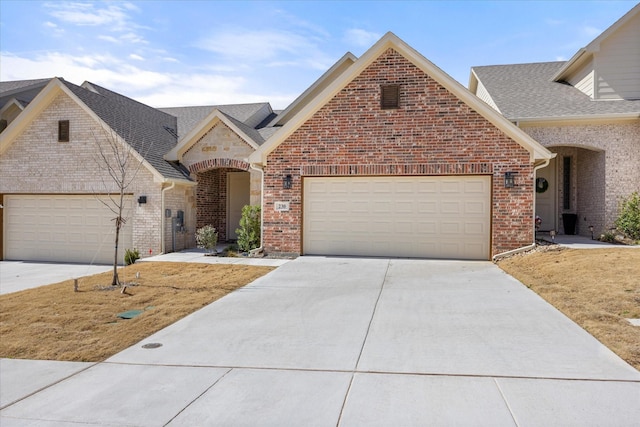 view of front of home with concrete driveway, brick siding, an attached garage, and a shingled roof