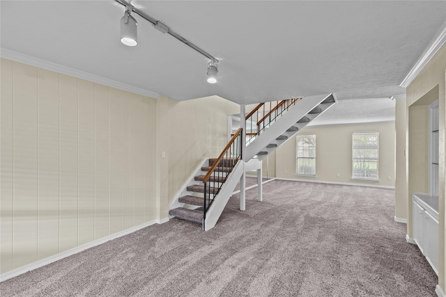 interior space with ornamental molding, baseboards, carpet flooring, and track lighting