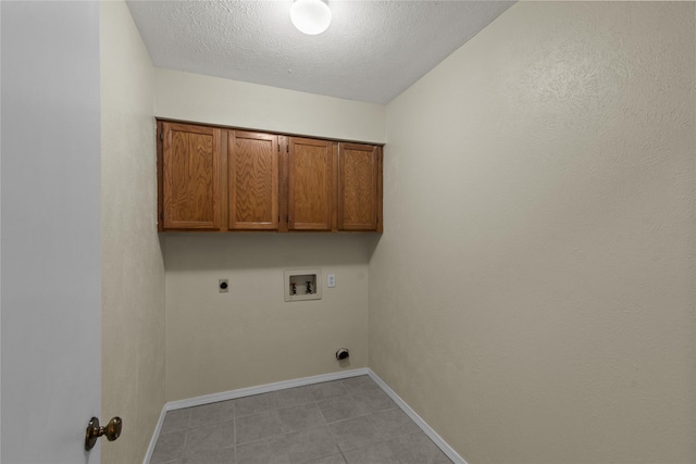 clothes washing area with a textured ceiling, hookup for a washing machine, hookup for an electric dryer, baseboards, and cabinet space