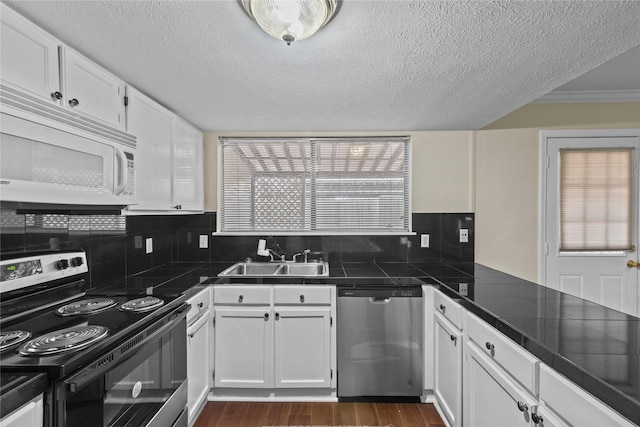 kitchen featuring dishwasher, white microwave, white cabinetry, a sink, and range with electric stovetop