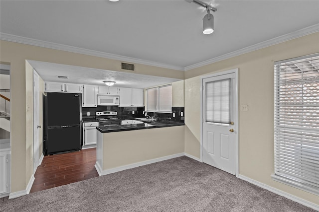 kitchen with visible vents, white microwave, freestanding refrigerator, a sink, and a peninsula