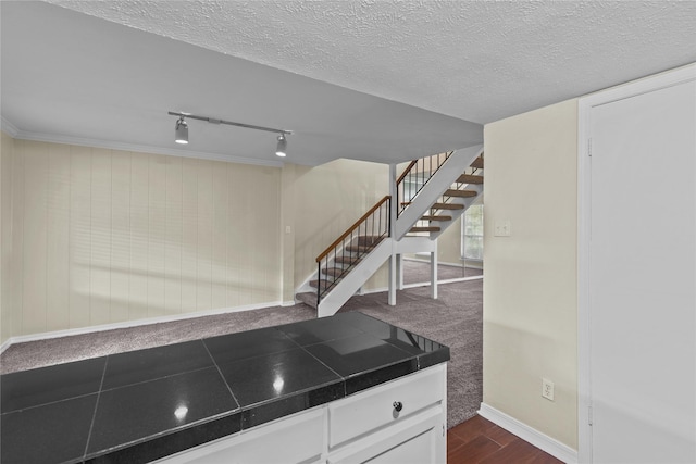 kitchen featuring tile counters, white cabinets, a textured ceiling, track lighting, and baseboards