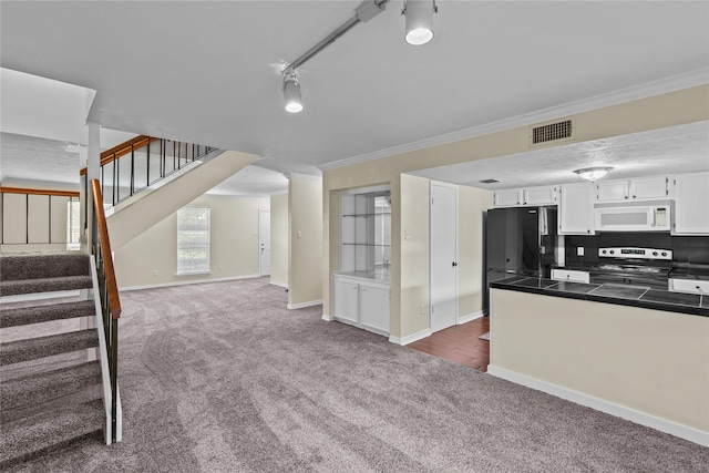 kitchen with visible vents, white microwave, freestanding refrigerator, stainless steel range with electric stovetop, and dark carpet