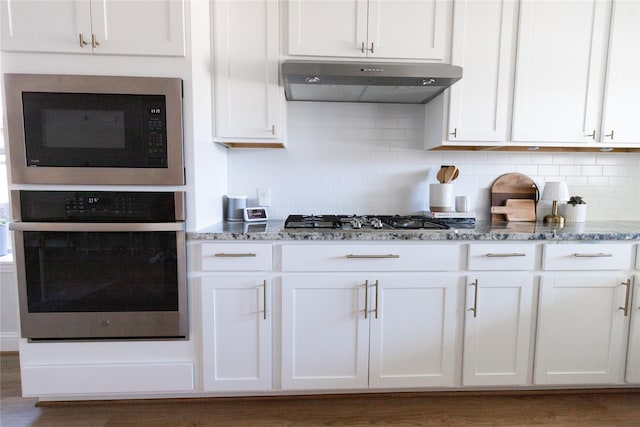 kitchen featuring stainless steel appliances, white cabinets, under cabinet range hood, and light stone countertops