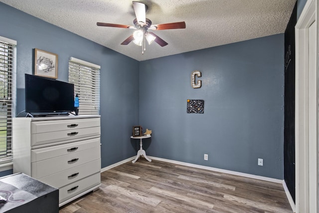 bedroom featuring a textured ceiling, wood finished floors, a ceiling fan, and baseboards