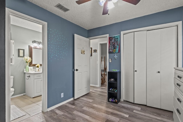 bedroom featuring baseboards, visible vents, a textured ceiling, and wood finished floors