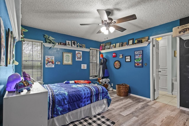 bedroom featuring a textured ceiling, wood finished floors, a ceiling fan, and baseboards