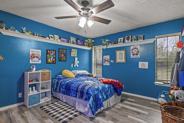 bedroom with a ceiling fan, a textured ceiling, baseboards, and wood finished floors