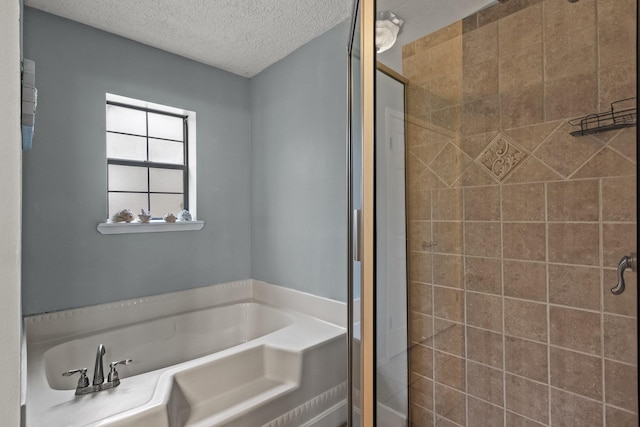 full bathroom with a stall shower, a textured ceiling, and a bath