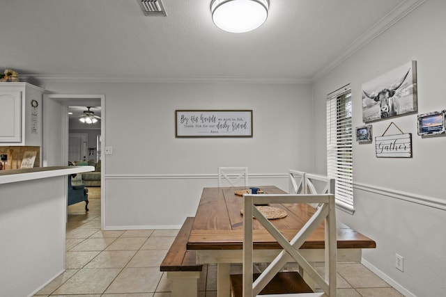 dining room with ceiling fan, light tile patterned flooring, visible vents, baseboards, and crown molding