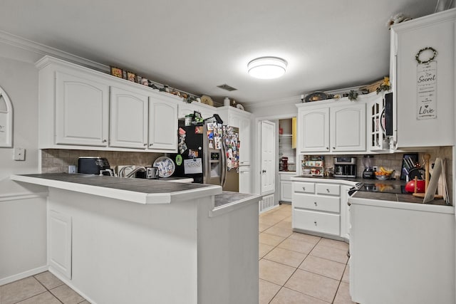 kitchen with light tile patterned floors, a peninsula, white cabinetry, stainless steel fridge with ice dispenser, and tasteful backsplash