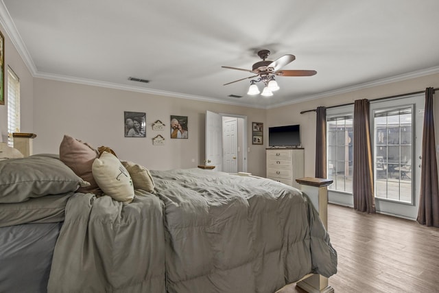 bedroom featuring ornamental molding, visible vents, ceiling fan, and wood finished floors