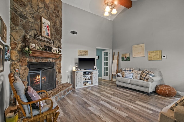 living room featuring ceiling fan, a fireplace, wood finished floors, visible vents, and baseboards