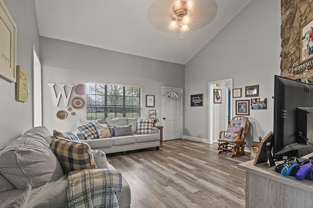 living area with high vaulted ceiling, wood finished floors, a ceiling fan, and baseboards