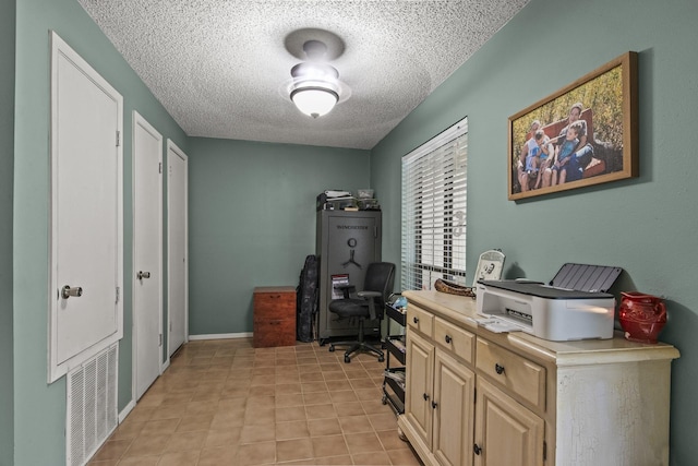 office area with visible vents, a textured ceiling, baseboards, and light tile patterned floors