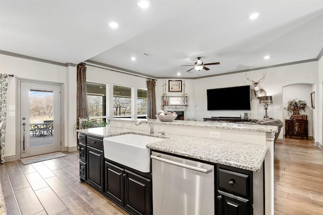 kitchen with open floor plan, dark cabinetry, dishwasher, and a sink