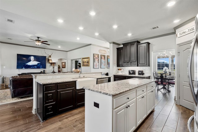 kitchen with crown molding, open floor plan, a sink, and a center island