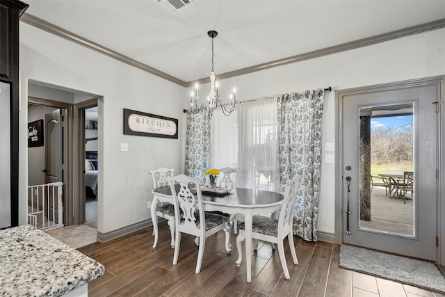 dining area with ornamental molding, wood finish floors, a chandelier, and baseboards