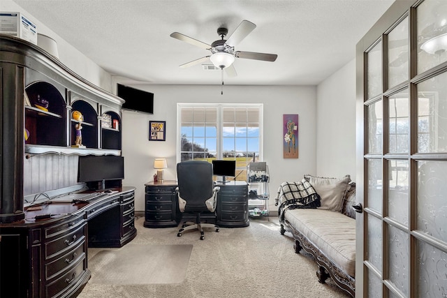 carpeted office with ceiling fan and a textured ceiling