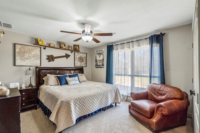 carpeted bedroom with a textured ceiling, ceiling fan, and visible vents